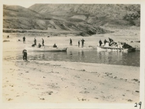 Image: Men working on and near small boats. Two boats heavily loaded with supplies